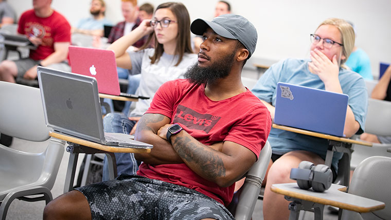 Three Missouri State students intently listening to the professor within the classroom.